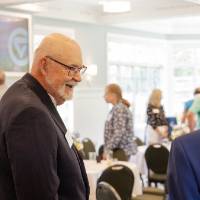 Gentleman with short white beard smiling at someone off camera